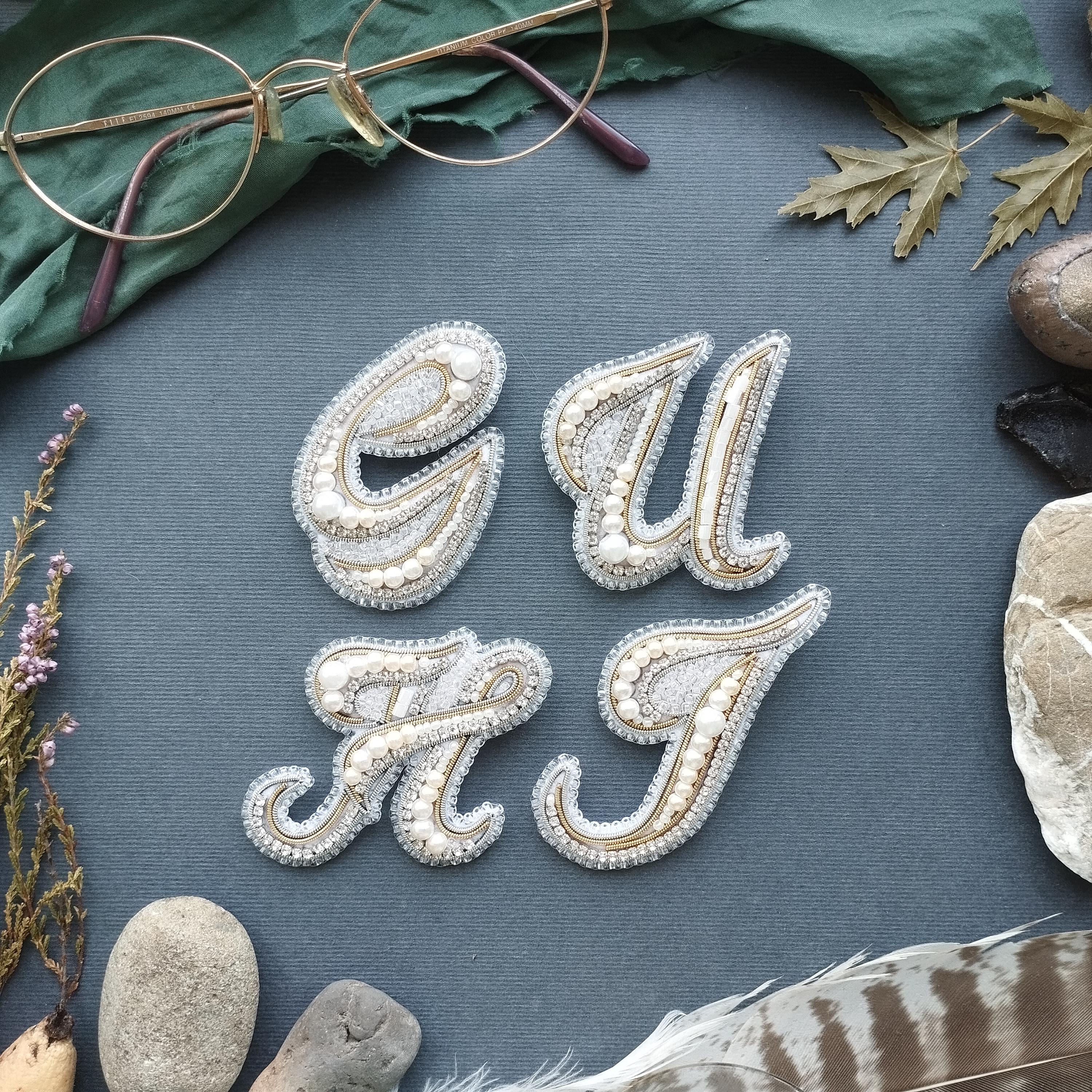 a close-up of a textured surface with various objects arranged around it, including a pair of glasses, leaves, feathers, and rocks.